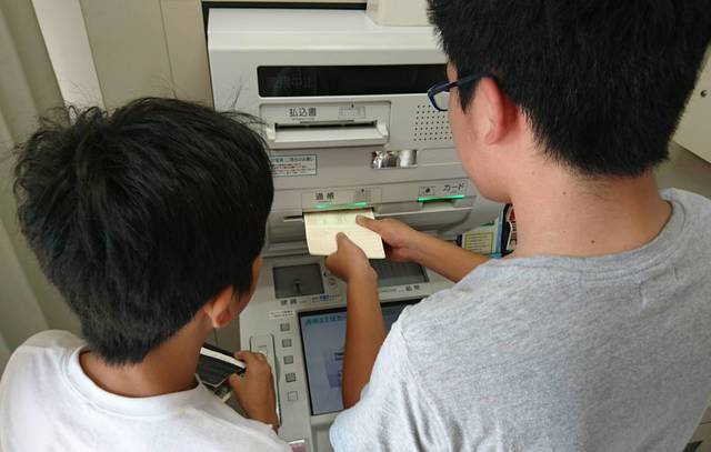 ゆうちょ銀行のATMで貯金をする子ども